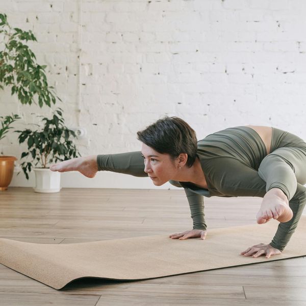 A woman unrolls her yoga mat in a bright, welcoming studio space.